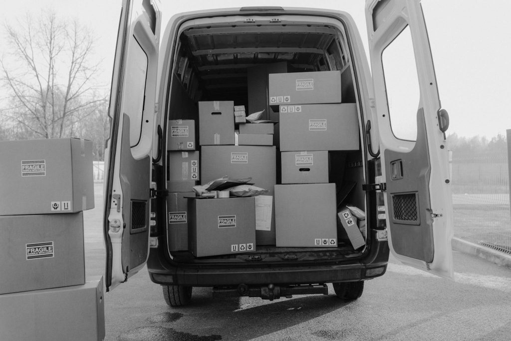 Open delivery van loaded with various boxes labeled as fragile, ready for shipment.
